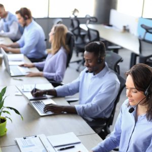 Young employee working with a headset and accompanied by her team